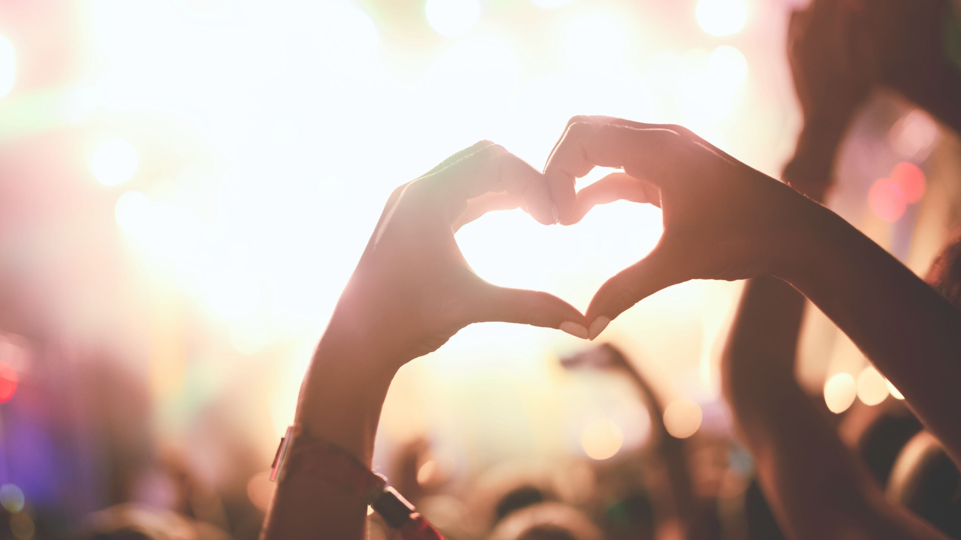 Vrouw maakt een hartje met haar handen tijdens een festival – symbool van dankbaarheid en verbinding bij TOUTESTBELLE.