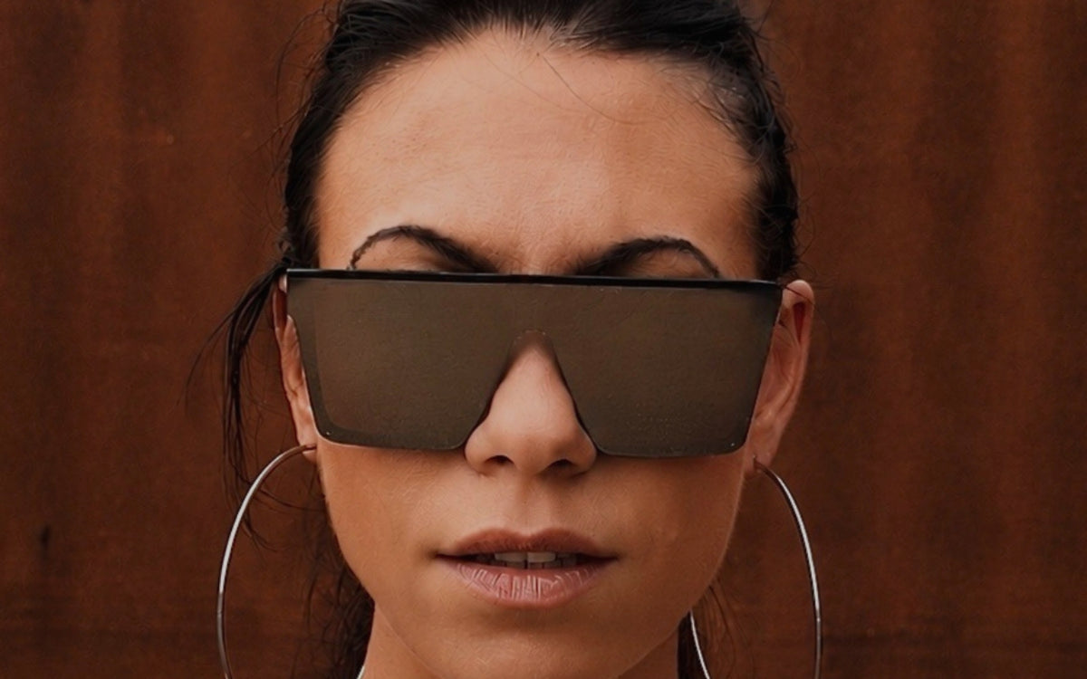 Model met een oversized festival zonnebril met donkere glazen en zwart montuur van TOUTESTBELLE.