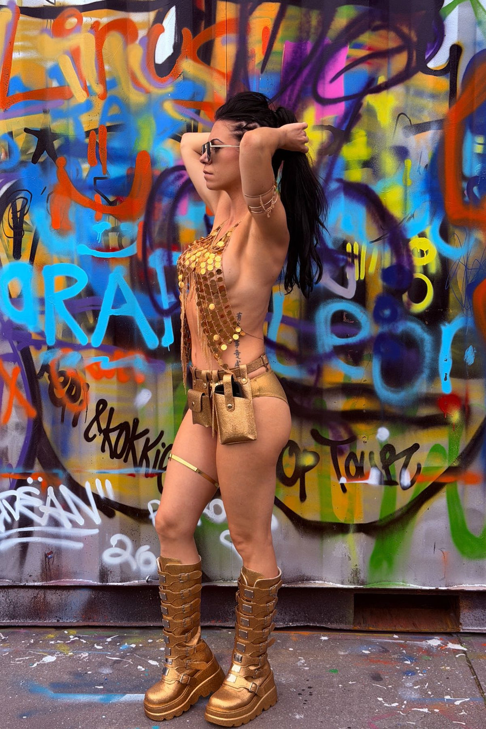 Model draagt de Festival Pailletten top Golden Hour in goud, gecombineerd met gouden statement boots en festival accessoires.