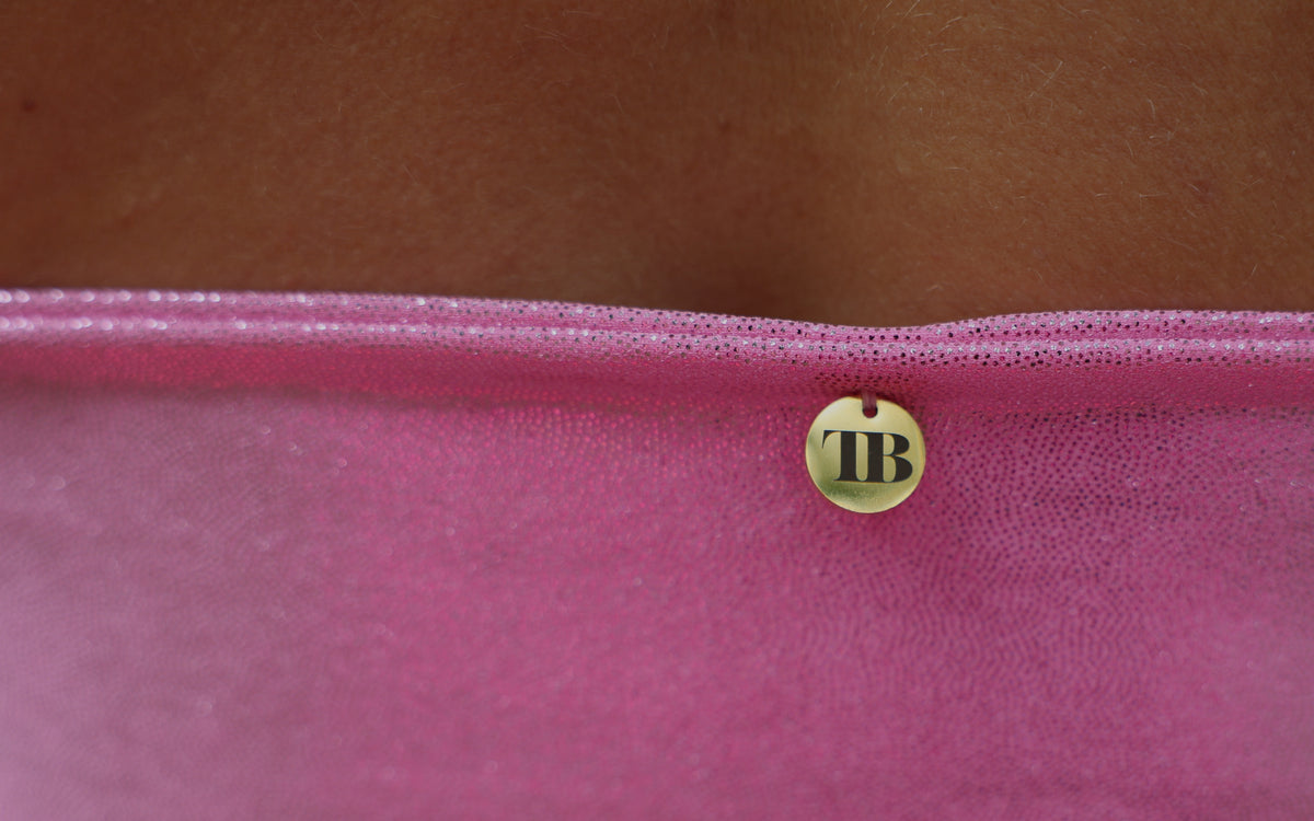 Close-up van een roze metallic festival top met gouden TOUTESTBELLE-label en glanzende stof.