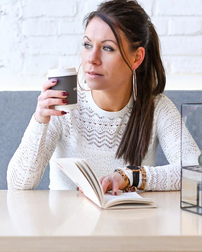 Renske, de oprichtster van TOUTESTBELLE, geniet van een koffiemoment terwijl ze schrijft en reflecteert; het gezicht achter het merk.