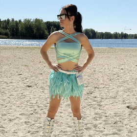 Model in TOUTESTBELLE festival outfit op het strand, mintgroene top en verenrok