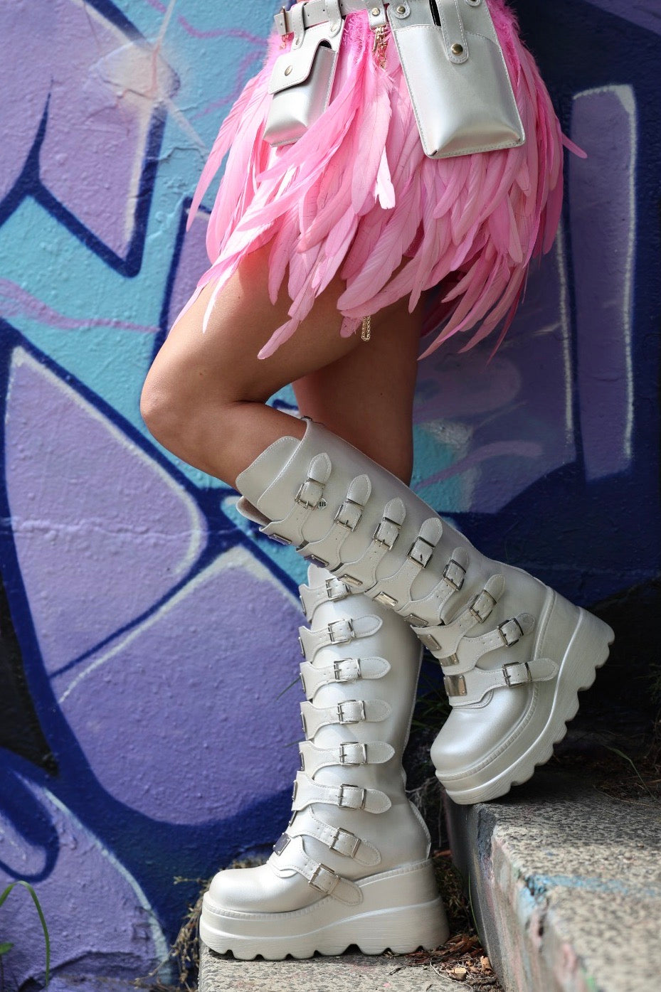 Close-up van zilveren festival boots van TOUTESTBELLE met daarboven een roze verenrokje, perfect voor een opvallende festival outfit.